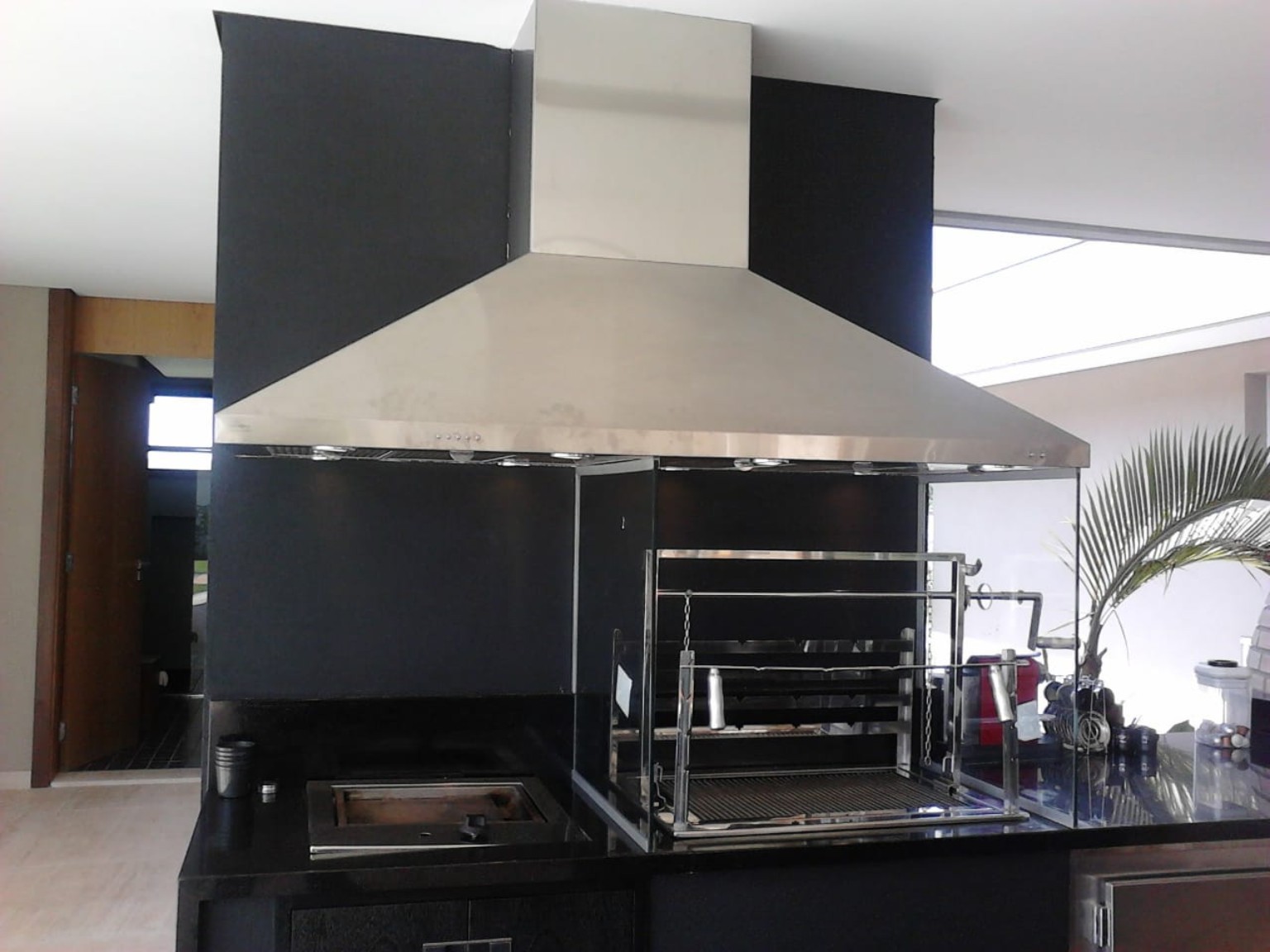 Coifa em aço inox instalada sobre churrasqueira em área gourmet