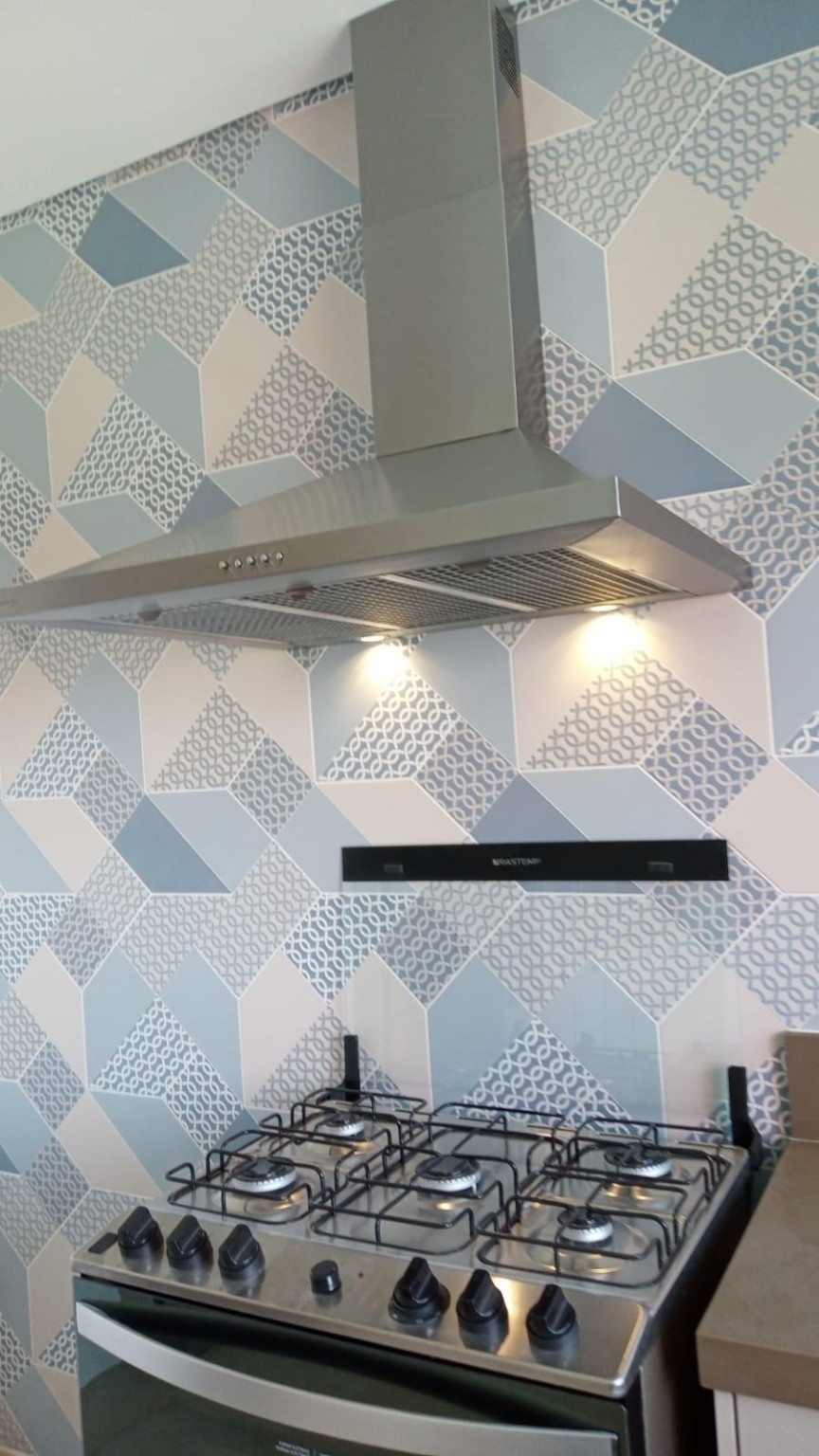 Coifa residencial em inox com filtros e iluminação instalada sobre fogão
